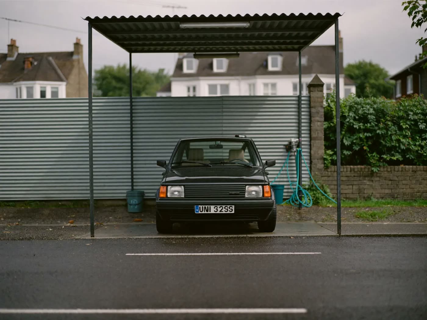 A finished car standing on the wet forecourt in front of the wash canopy